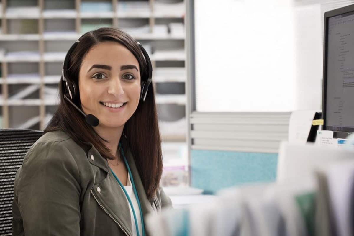 Frau mit Headset lächelt in Kamera